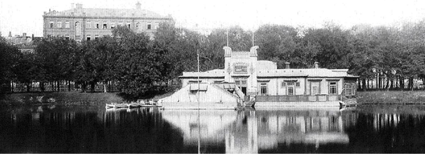1913 г. Павильон лодочной станции на Патриаршем пруду. На заднем плане — дом № 7 по Ермолаевскому переулку. Правее, за деревьями — перекрёсток, где Берлиоз попал под трамвай